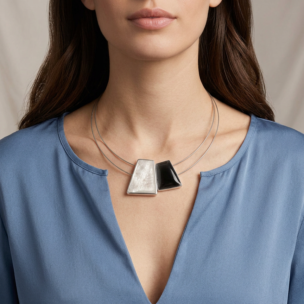 Model with long hair wearing the necklace against her skin with a blue open-neck blouse