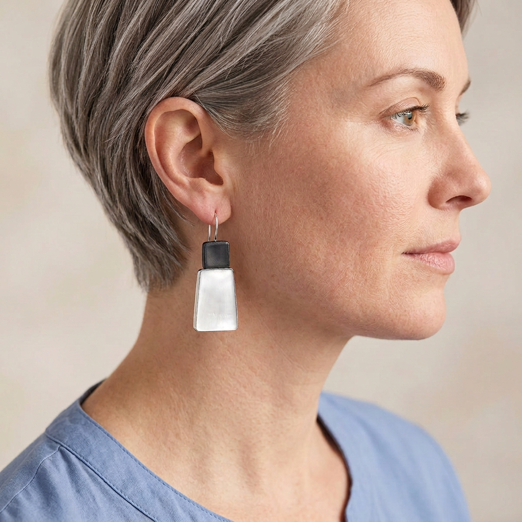 Model with short silver-grey hair wearing charcoal and white earrings